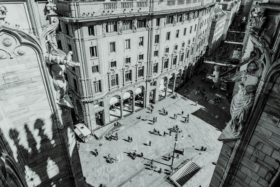 Distant anonymous pedestrians crossing a quiet European square seen from above